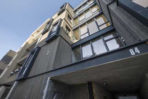Moderne Wohnhausfassade aus Holz und Glas, Hausnummer 84, Blick nach oben.