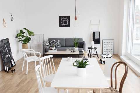 Helles Wohnzimmer mit grauem Sofa, weißen Möbeln und Pflanzen, minimalistisch.