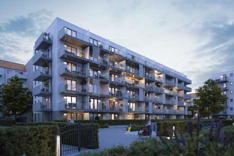 Modernes Wohnhaus mit Balkonen, beleuchtet in der Abenddämmerung.