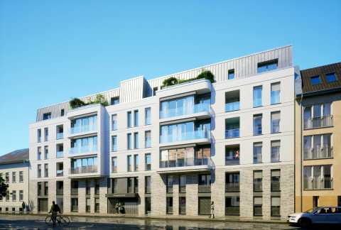 Modernes, mehrstöckiges Wohngebäude mit Balkonen und großen Fenstern bei Sonnenschein.