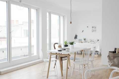 Helles, modernes Esszimmer mit großen Fenstern, weißen Möbeln und Pflanzen.