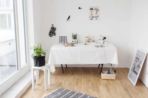Heller Raum mit Holzboden, Esstisch, Pflanze, Küchenutensilien und Wanddeko.