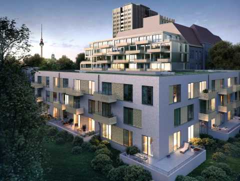 Modernes Wohngebäude mit Balkonen, beleuchtet bei Dämmerung, im Grünen.