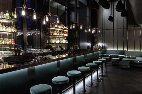 Moderne Bar mit beleuchtetem Tresen, Hockern und gemütlichen Sitzbereichen.