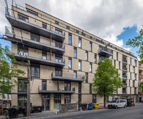 Modernes, mehrstöckiges Wohngebäude mit Balkonen und Straßenansicht.