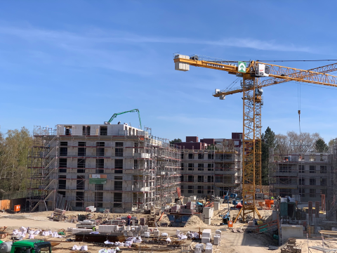 Baustelle mit Kran und mehreren im Bau befindlichen Mehrfamilienhäusern.