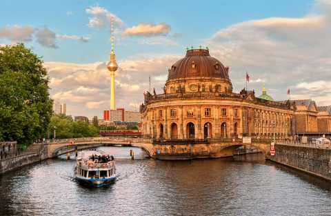 Boot auf der Spree vor dem Bode-Museum und Berliner Fernsehturm bei Abendlicht.