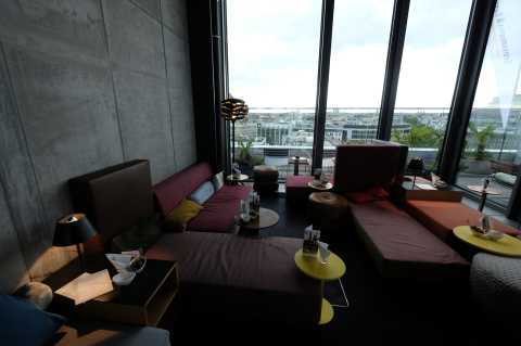 Moderne Lounge mit bunten Sofas und großen Fenstern mit Stadtblick.