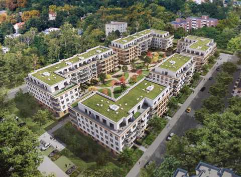 Mehrere moderne Wohngebäude mit begrünten Dächern und Innenhof aus der Luft.