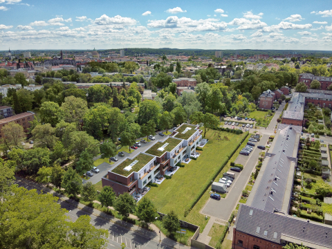 Luftbild von Wohnhäusern mit begrünten Dächern, umgeben von viel Grün.