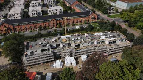Baustelle eines mehrstöckigen Gebäudes mit Gerüsten und Kran in Wohngegend.