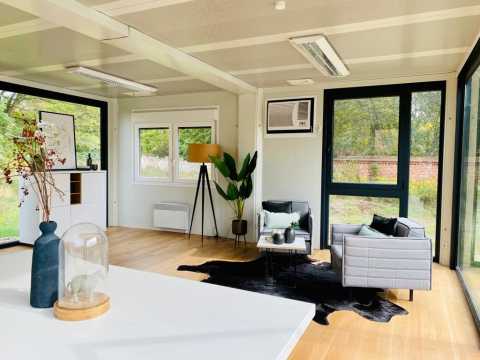 Modernes Wohnzimmer mit zwei grauen Sesseln, großen Fenstern und Dekoration.