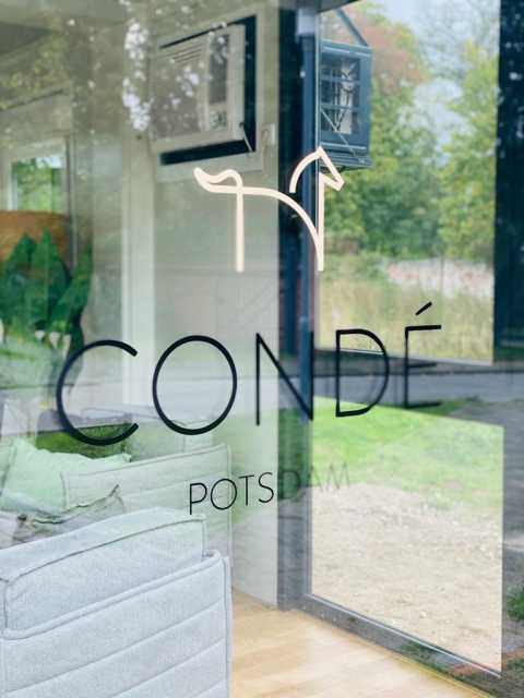 Glasfront mit Logo „Condé Potsdam“ und minimalistischer Pferdezeichnung.
