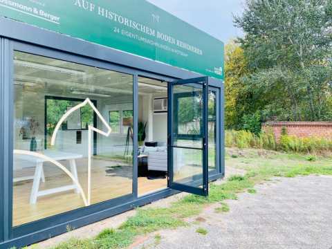 Moderner Verkaufscontainer mit offen stehender Tür und großem Fenster.