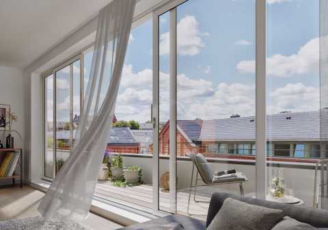Helles Wohnzimmer mit Glasfront, Blick auf Balkon, Pflanzen und Dächer.