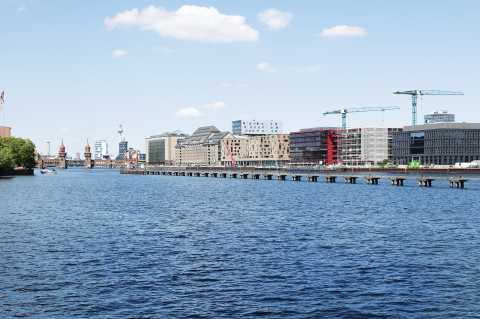 Blick auf Spree, moderne Gebäude, Baukräne und Oberbaumbrücke in Berlin.