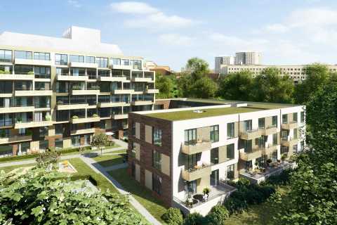 Moderne Wohngebäude mit Balkonen, Grünflächen und Bäumen im Vordergrund.