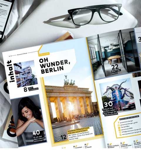 Brille, Smartphone und Magazin mit Berlin-Titelstory auf einem weißen Tisch.