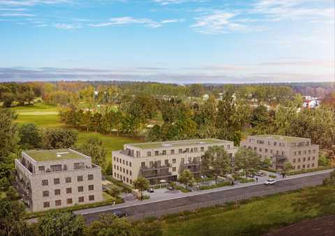 Drei moderne Wohngebäude am Waldrand mit vielen Bäumen und blauen Himmel.