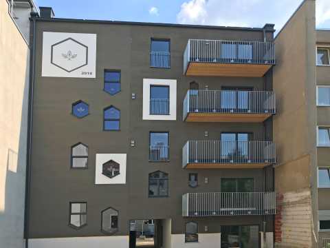 Modernes Wohnhaus mit drei Balkonen und vielen sechseckigen Fenstern.