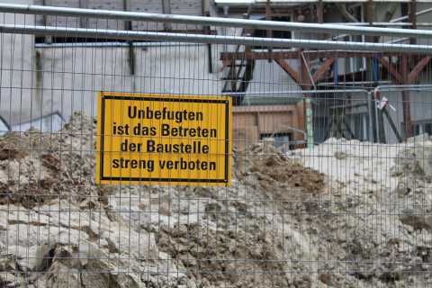 Zaun mit Schild: „Unbefugten ist das Betreten der Baustelle streng verboten.“
