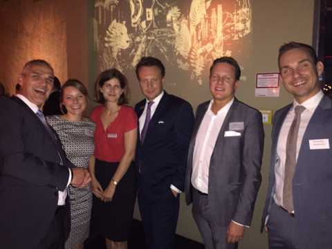 Sechs Personen in Businesskleidung stehen zusammen und lächeln in die Kamera.