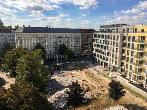 Baustelle zwischen alten und modernen Wohnhäusern an einer sonnigen Straße.
