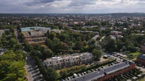 Luftaufnahme einer Stadt mit vielen Bäumen und einer Baustelle im Vordergrund.