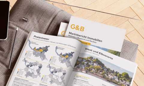 Marktbericht Immobilien mit Karten und Fotos auf grauem Stoff, Stift daneben.