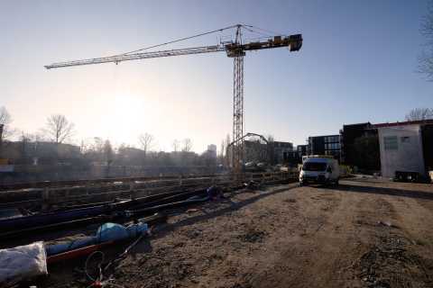 Baustelle mit Kran, Lieferwagen und Baumaterialien bei Sonnenaufgang