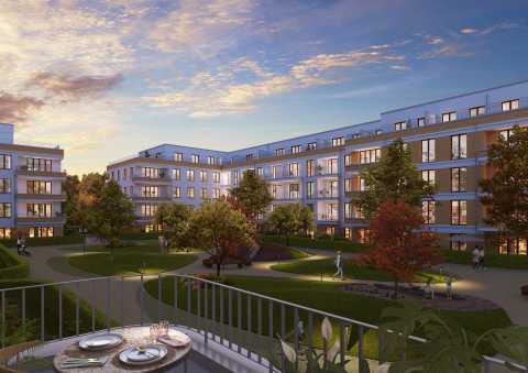 Moderne Wohnanlage mit begrüntem Innenhof und Menschen bei Sonnenuntergang.