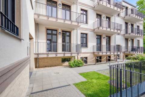 Moderner Wohnhaus-Innenhof mit Balkonen, Fenstern, Wegen und etwas Grünfläche.