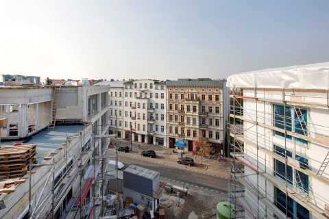 Straßenszene mit Altbauten und Baustellen auf beiden Seiten der Straße.