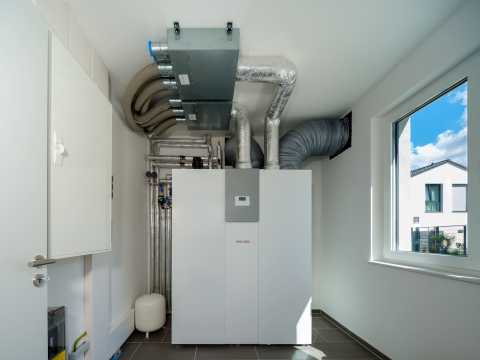 Moderne Heizungsanlage mit Lüftungsrohren in einem hellen Technikraum.