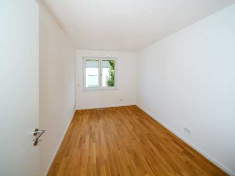 Leerer Raum mit Holzfußboden, weißen Wänden und einem Fenster.