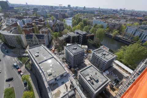 Blick auf eine Baustelle mit mehreren Gebäuden und einem Fluss im Hintergrund.