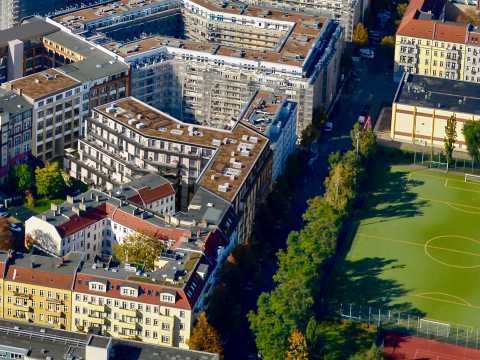 Luftaufnahme von Wohnhäusern neben einem Sportplatz mit Fußballfeld in der Stadt.