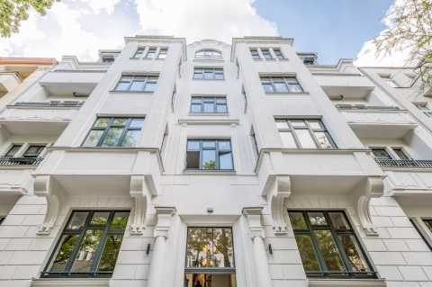 Blick von unten auf eine moderne, weiße Fassade eines mehrstöckigen Hauses.