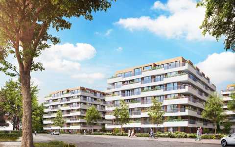 Moderne Wohngebäude mit Balkonen und begrünten Anlagen bei sonnigem Himmel.