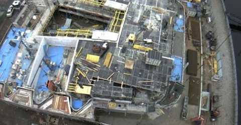 Luftbild einer Baustelle mit Baumaterialien und unfertigen Gebäudestrukturen.