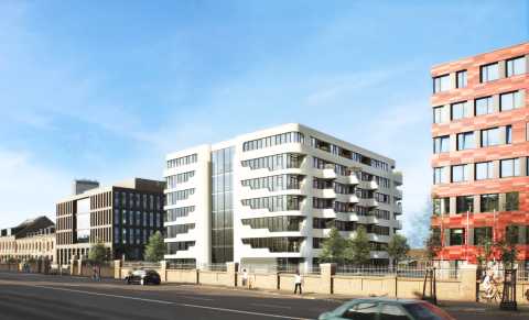 Moderne Wohnhäuser und Büros an einer sonnigen Straße mit Autos und Fahrrädern.