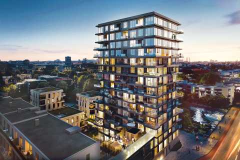 Modernes Hochhaus mit Glasfassade bei Sonnenuntergang, Stadt im Hintergrund.