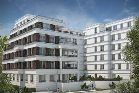 Modernes Mehrfamilienhaus mit Balkonen, großem Garten und blauen Himmel