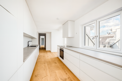 Helle, moderne Einbauküche mit weißen Fronten und großem Fenster.