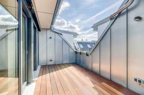 Moderne Dachterrasse mit Holzboden und Metallwänden unter blauem Himmel