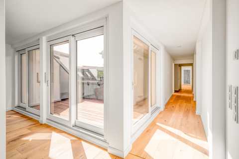 Heller Flur mit Holzboden, großen Fenstern und Zugang zur Terrasse.