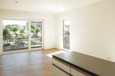 Helles, leeres Zimmer mit großen Fenstern und Blick ins Grüne