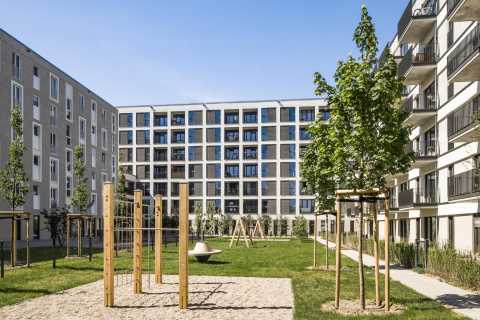 Moderner Wohnhof mit Spielplatz, Bäumen und mehrstöckigen Wohngebäuden.