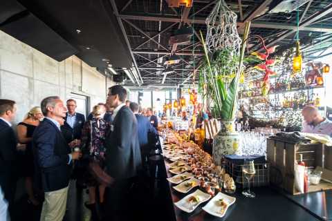 Menschen bei einem eleganten Empfang mit Getränken und Fingerfood an einer Bar.