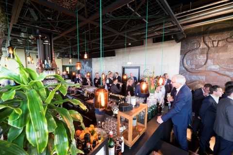 Große Gruppe Menschen in eleganter Bar, viele stehen und unterhalten sich.